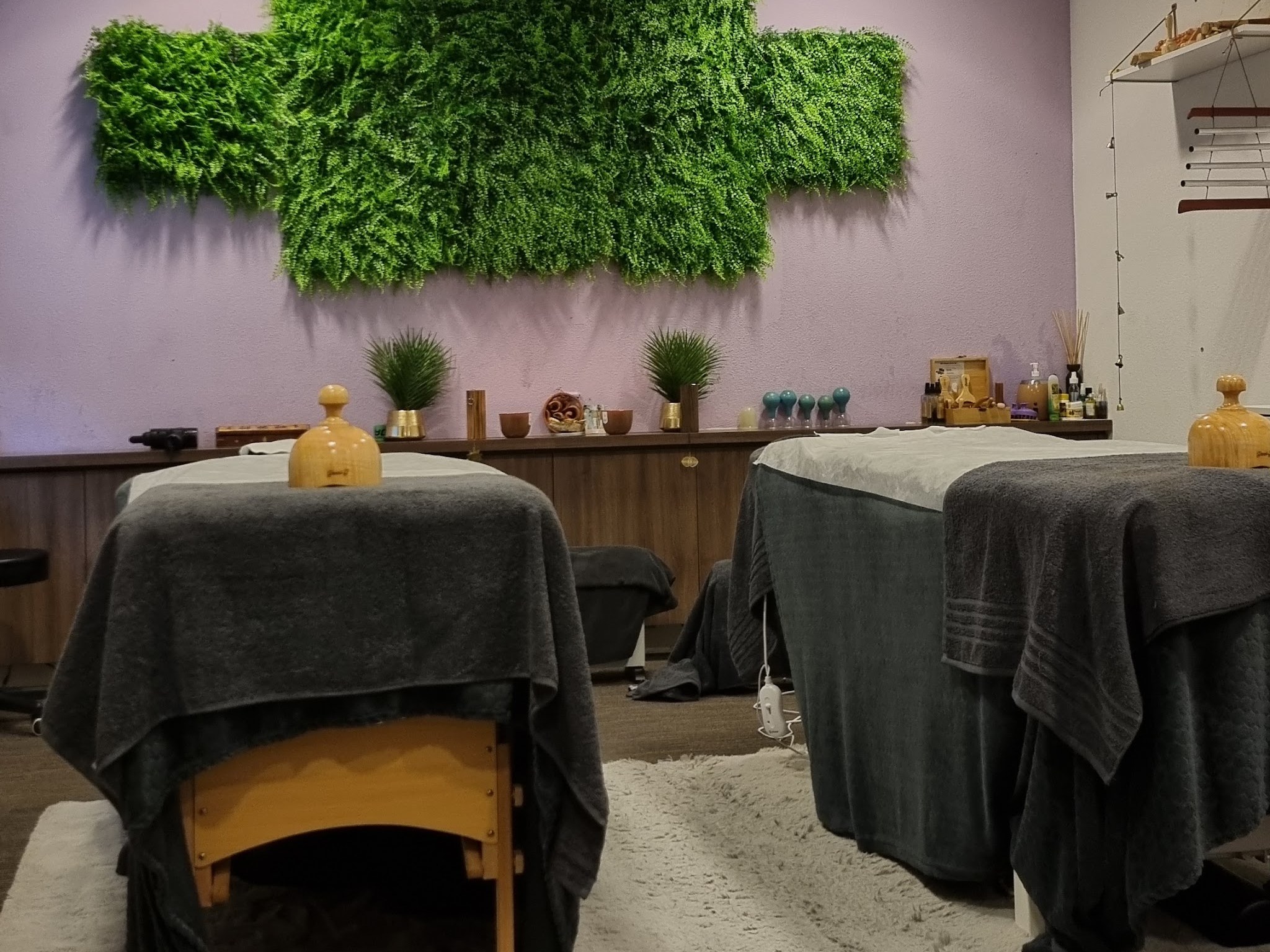 De behandelruimte met twee tafels onder grijze doeken, een lila wand en een groene mooswand